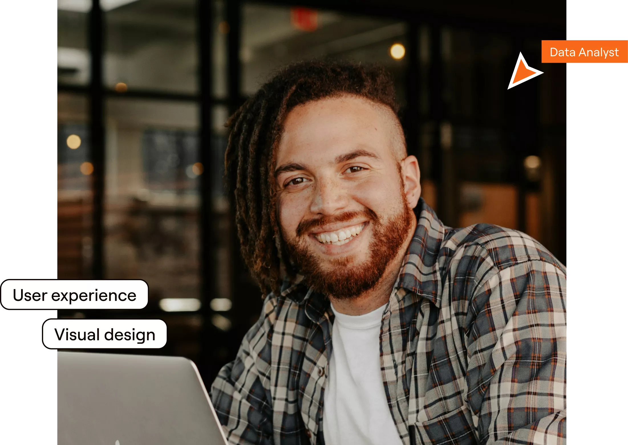 A man with dreadlocks smiles while working on his laptop, showcasing a moment of joy and productivity.